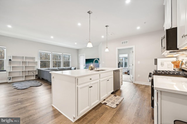 kitchen with white cabinetry, stainless steel appliances, a center island with sink, and pendant lighting