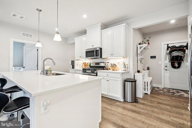 kitchen with a center island with sink, sink, white cabinetry, and appliances with stainless steel finishes