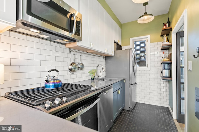 kitchen featuring appliances with stainless steel finishes, dark tile patterned floors, decorative light fixtures, white cabinets, and decorative backsplash