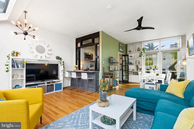 living room with wood-type flooring and ceiling fan with notable chandelier