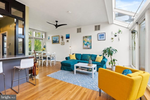 living room with hardwood / wood-style floors, ceiling fan, and a skylight