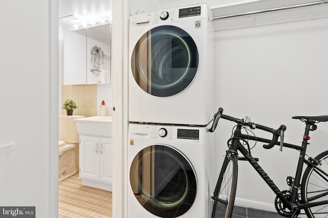 washroom featuring stacked washing maching and dryer and tile patterned floors