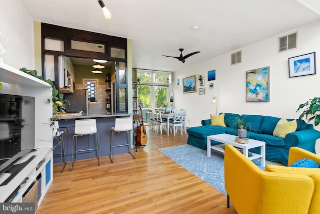 living room featuring light wood-type flooring and ceiling fan