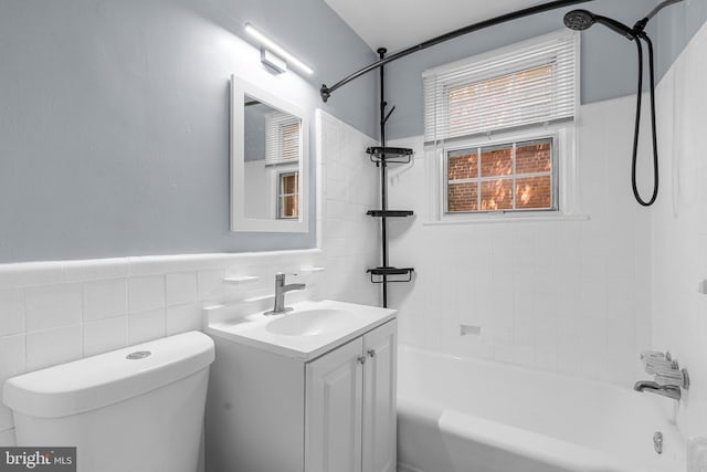 full bathroom featuring vanity, tiled shower / bath, toilet, and tile walls