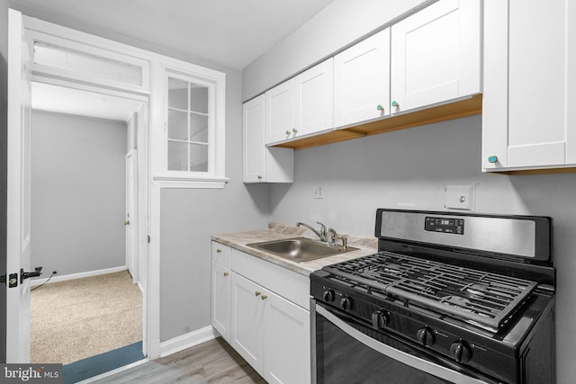 kitchen featuring gas range, white cabinetry, sink, and light wood-type flooring