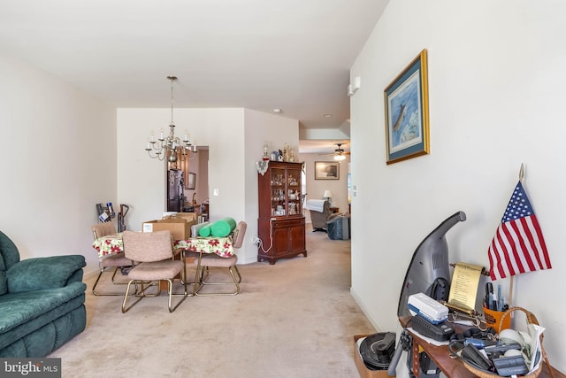 living area with ceiling fan with notable chandelier and light colored carpet