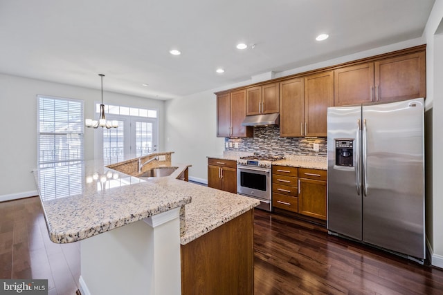 kitchen with appliances with stainless steel finishes, sink, dark hardwood / wood-style flooring, pendant lighting, and an inviting chandelier