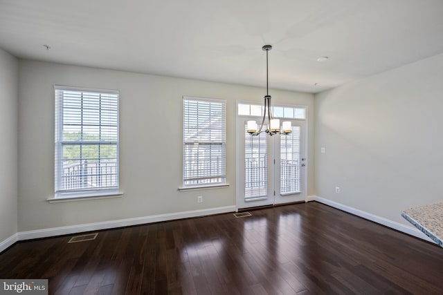 unfurnished dining area with dark hardwood / wood-style floors, a chandelier, and a wealth of natural light