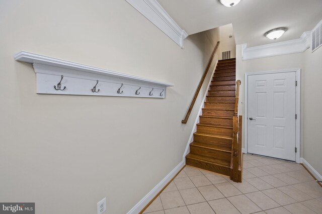 staircase featuring crown molding and tile patterned flooring