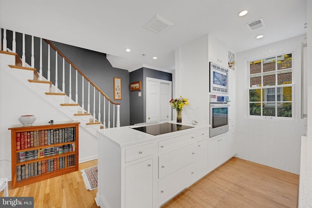 kitchen featuring kitchen peninsula, white cabinets, stainless steel appliances, and light hardwood / wood-style floors