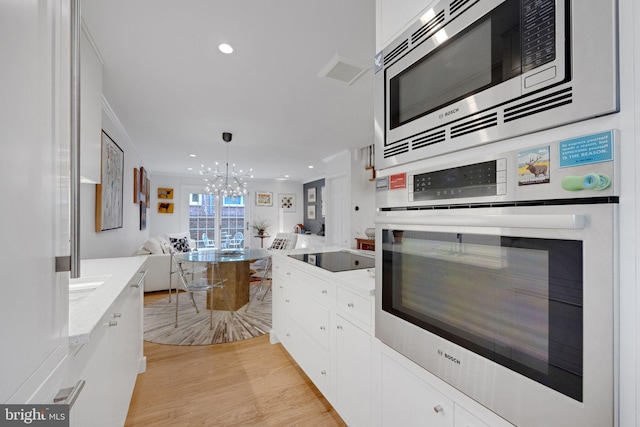 kitchen featuring white cabinets, light stone counters, stainless steel appliances, and light hardwood / wood-style flooring