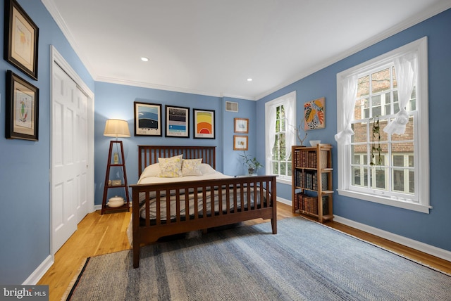 bedroom featuring a closet, wood-type flooring, and ornamental molding