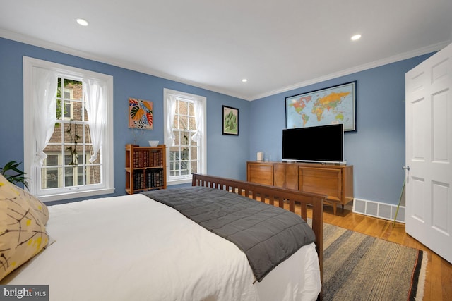 bedroom featuring crown molding and light hardwood / wood-style flooring