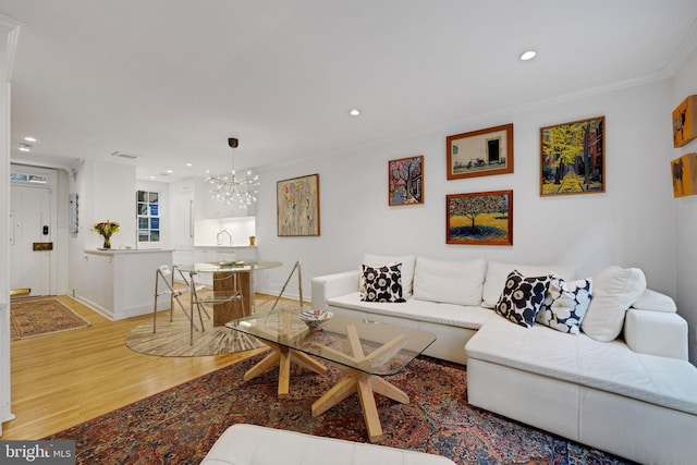 living room featuring hardwood / wood-style flooring, an inviting chandelier, and crown molding