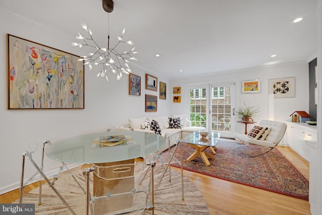 dining room with crown molding, an inviting chandelier, and light wood-type flooring