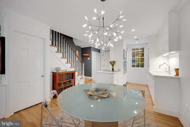 dining room with a notable chandelier, light hardwood / wood-style floors, crown molding, and sink