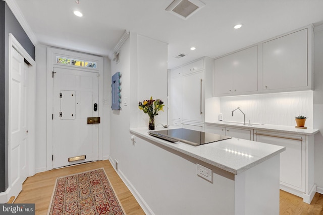 kitchen with kitchen peninsula, black electric cooktop, white cabinets, and light wood-type flooring