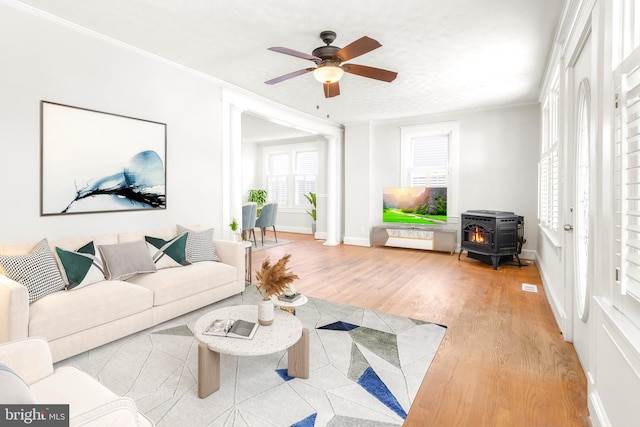 living room featuring ornamental molding, a wood stove, hardwood / wood-style floors, and ceiling fan