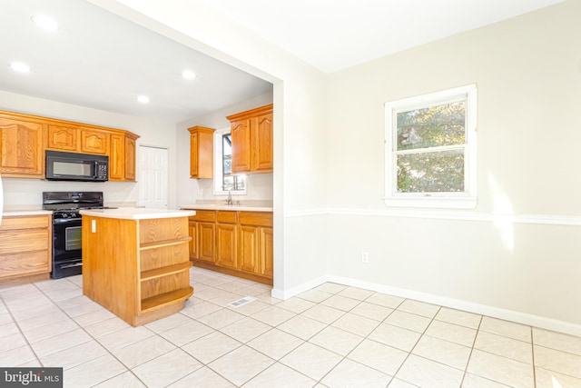 kitchen featuring black appliances, a center island, and light tile patterned floors