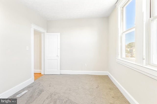 carpeted spare room with a textured ceiling