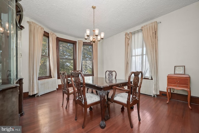 dining room with a textured ceiling, radiator, dark hardwood / wood-style floors, and a notable chandelier