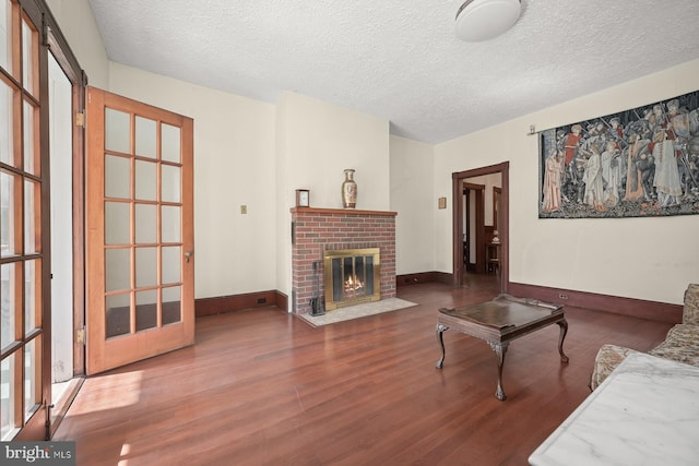 living room featuring a textured ceiling, dark hardwood / wood-style flooring, and a fireplace