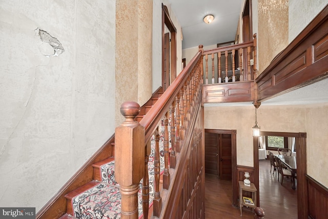 stairway featuring wood-type flooring and a towering ceiling