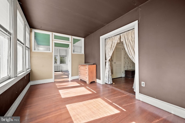 empty room featuring hardwood / wood-style flooring, plenty of natural light, and radiator heating unit