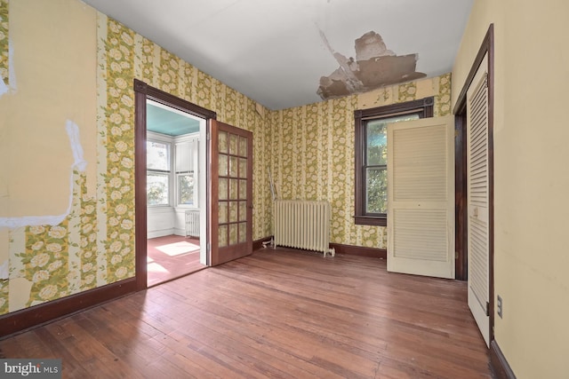 spare room featuring dark hardwood / wood-style flooring, radiator heating unit, and a wealth of natural light