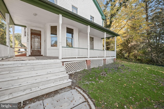 view of exterior entry with a yard and a porch