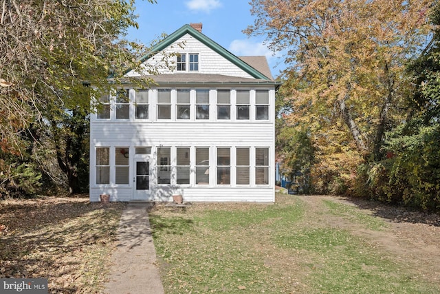 rear view of house featuring a sunroom and a lawn