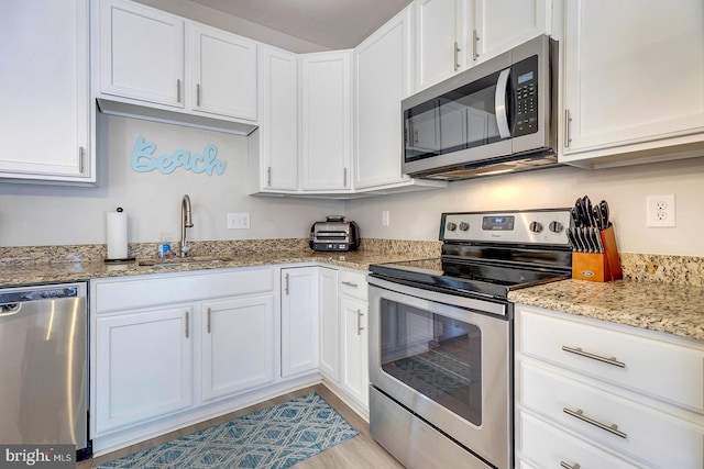 kitchen with sink, white cabinetry, stainless steel appliances, and light wood-type flooring