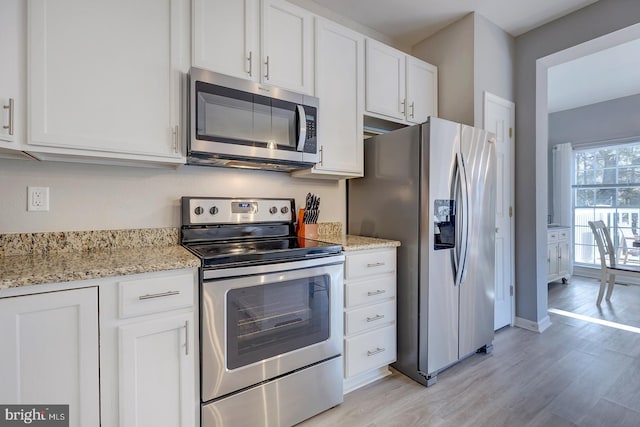 kitchen with stainless steel appliances, light stone countertops, light wood-type flooring, and white cabinets