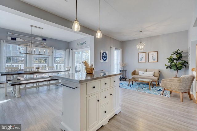 kitchen featuring light hardwood / wood-style flooring, white cabinetry, a kitchen island, and pendant lighting