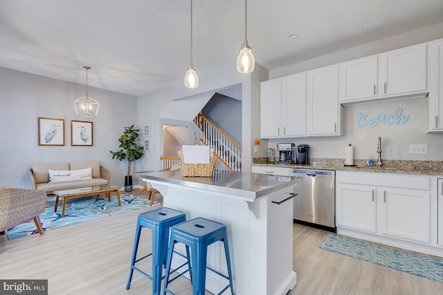 kitchen with dishwasher, light wood-type flooring, a kitchen bar, hanging light fixtures, and white cabinets