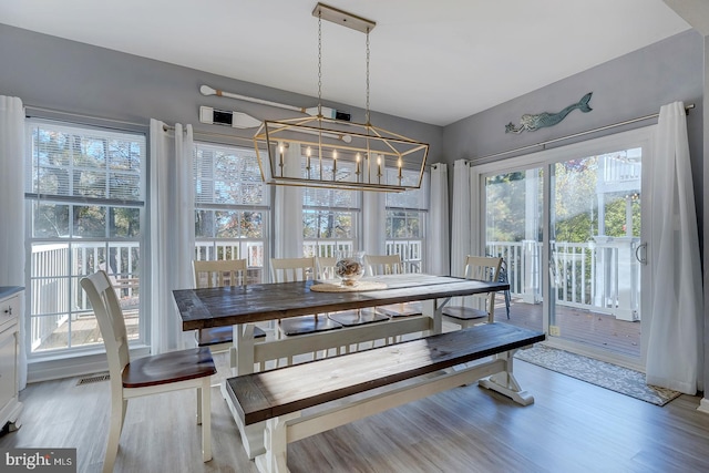 dining area featuring light wood-type flooring, a notable chandelier, and plenty of natural light