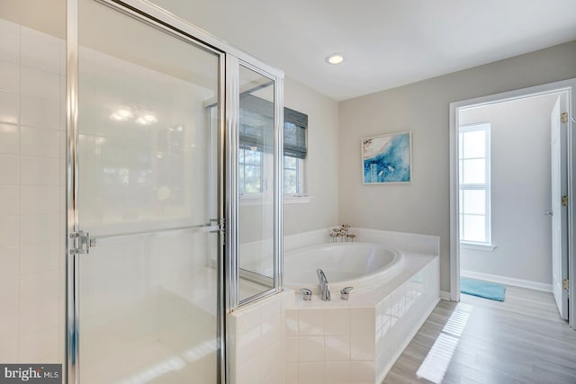 bathroom with independent shower and bath and wood-type flooring