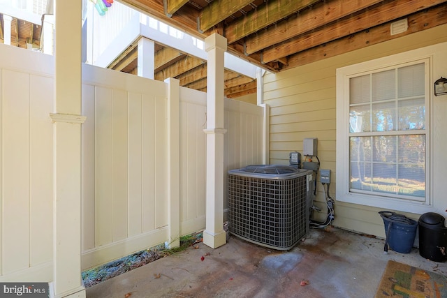 exterior details with central air condition unit, concrete flooring, and wooden walls