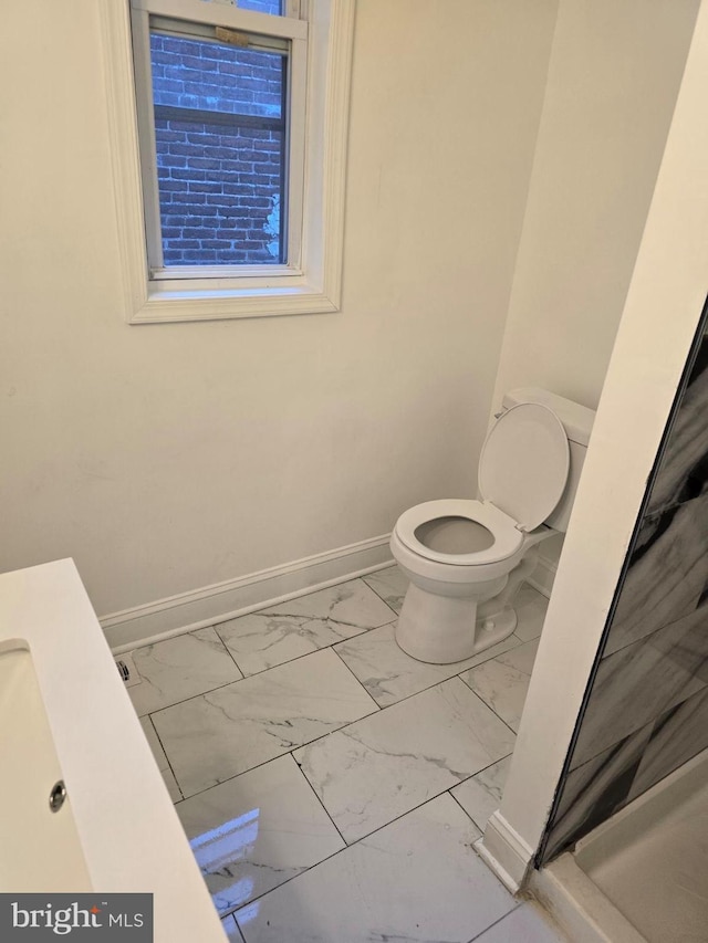 bathroom featuring marble finish floor, toilet, and baseboards