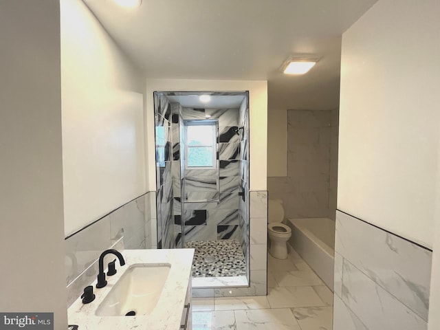 full bath featuring marble finish floor, tile walls, toilet, a tile shower, and vanity