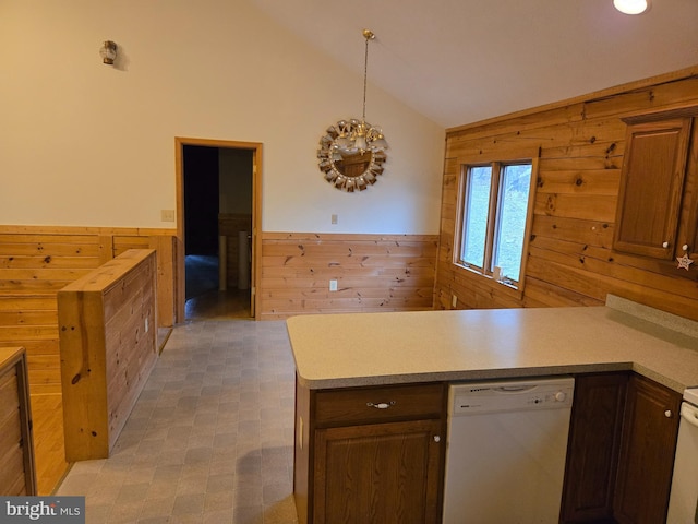 kitchen with a peninsula, wood walls, and white dishwasher