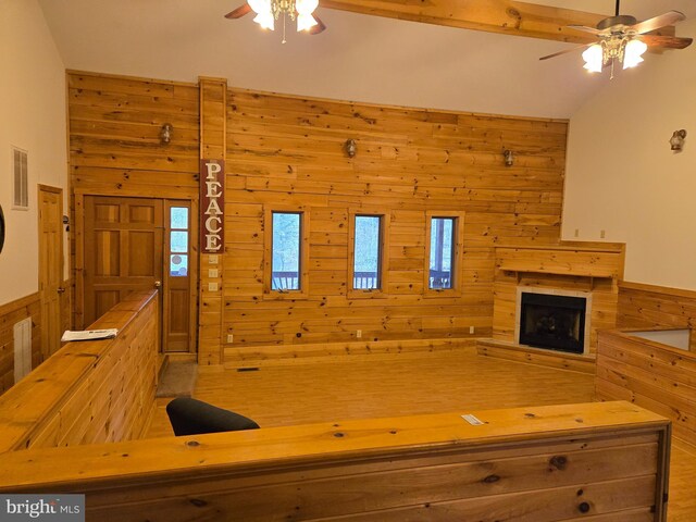 unfurnished living room featuring wooden walls, visible vents, a fireplace, and ceiling fan