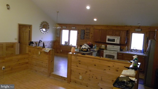 kitchen featuring sink, hanging light fixtures, white appliances, light hardwood / wood-style flooring, and lofted ceiling