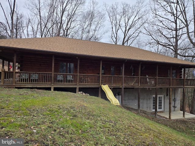 rear view of property with log siding, a wooden deck, and a lawn