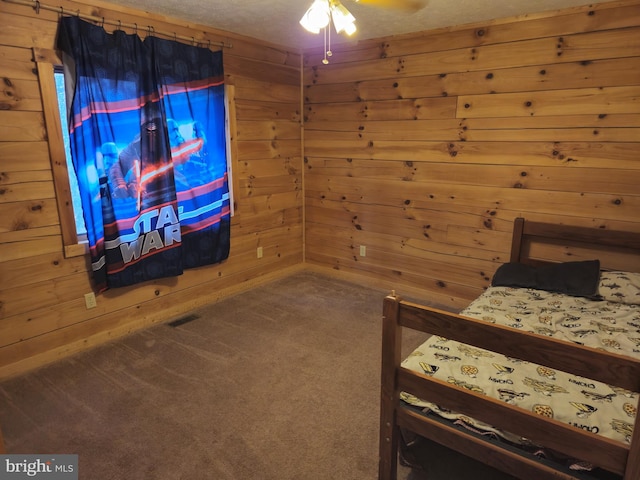 bedroom with wooden walls, visible vents, and carpet