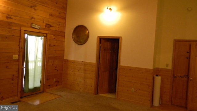 carpeted entrance foyer with wood walls