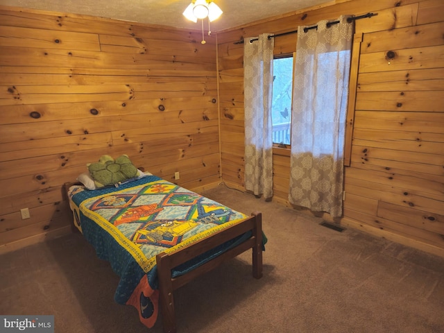 carpeted bedroom with wood walls and visible vents