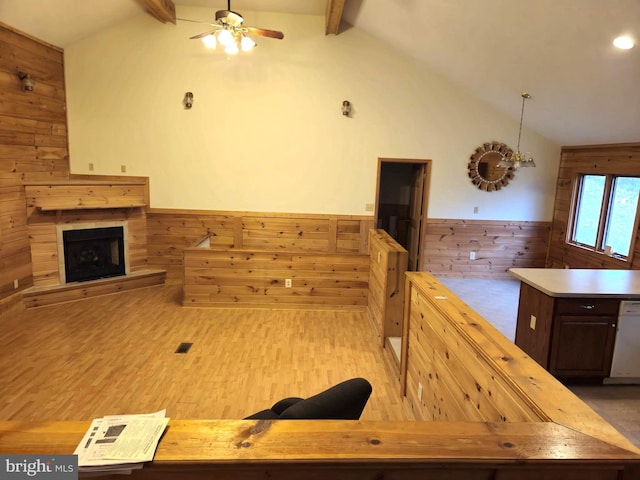 kitchen with lofted ceiling with beams, wood walls, wainscoting, and ceiling fan