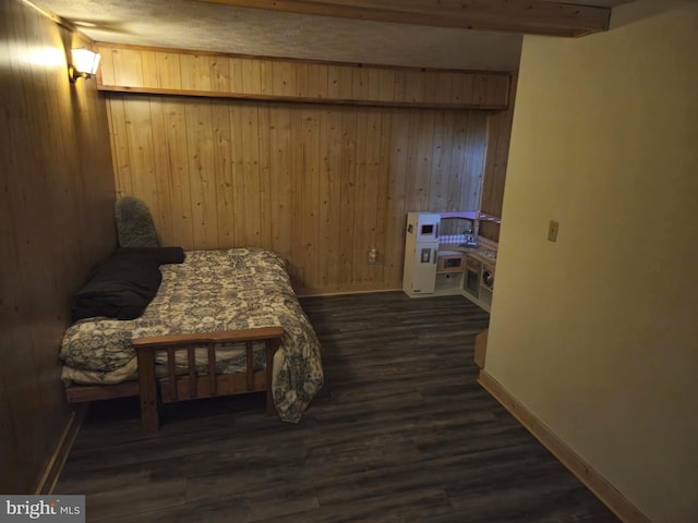 bedroom featuring baseboards, wood walls, and dark wood-type flooring