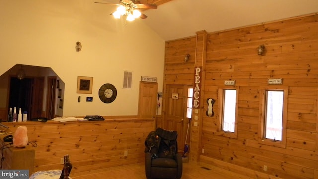 interior space featuring ceiling fan, wooden walls, light hardwood / wood-style flooring, and lofted ceiling